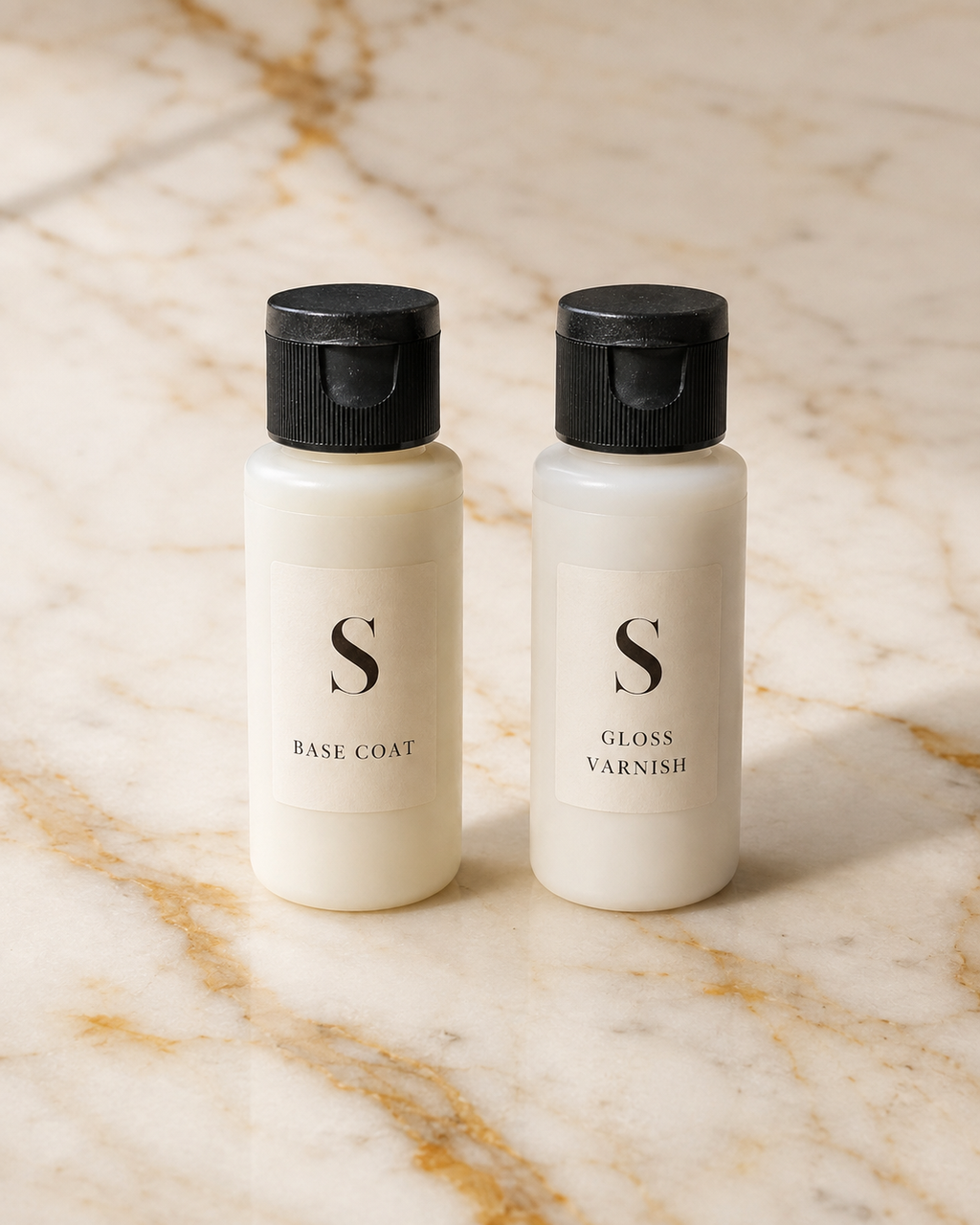 Two small white bottles with black caps labeled 'S BASE COAT' and 'S GLOSS VARNISH' standing side by side on a beige marble surface with gold veining.